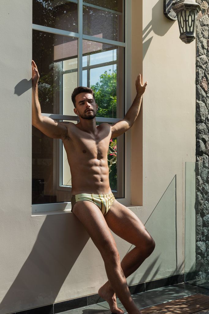 Dive into style with Smithers' newest swimwear release: a vibrant striped yellow and brown swimsuit worn by a charming and toned young man.